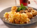 Pyszna surówka z kiszonej kapusty z marchewką, podana z duszonymi pieczarkami i kluskami śląskimi, ozdobiona miętą.