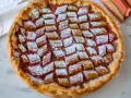 Tarta z rabarbarem posypana cukrem pudrem, obok łodygi rabarbaru.