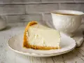 Pyszny sernik z mlekiem skondensowanym na kruchym spodzie, obok filiżanka kawy.