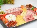 Deska wędlin jak przygotować: różnorodne sery, wędliny, oliwki, pomidorki i papryczki chili. Idealna na spotkanie.
