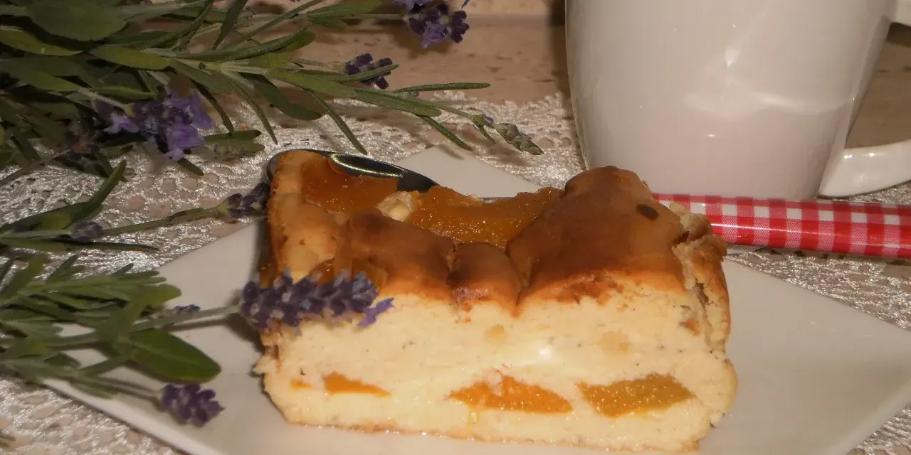Pyszny sernik z brzoskwiniami, udekorowany gałązką lawendy, czeka na kawę.