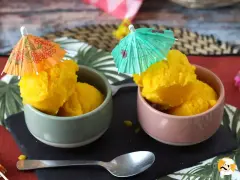 Dwa pucharki z pysznym, żółtym sorbetem, ozdobione parasolkami. Idealne na upalne dni, pokazują, jak zrobić sorbet.