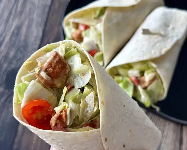 Pyszna tortilla z kurczakiem, sałatą, pomidorkami i sosem. Idealna na szybki lunch.