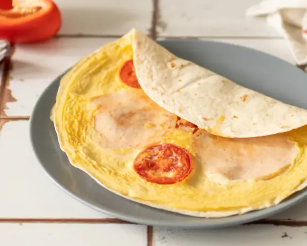 Pyszna tortilla z jajkiem, pomidorem i szynką, gotowa do zjedzenia.