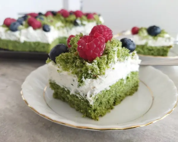 Zielony, puszysty biszkopt z kremem mascarpone, ozdobiony malinami i borówkami. To ciasto leśny mech na dużą blachę, które zachwyca smakiem i wyglądem.