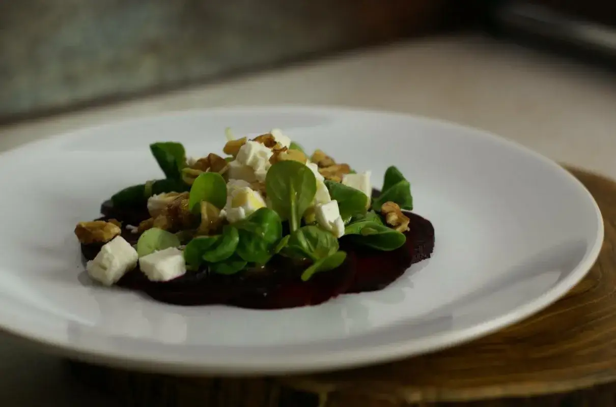 Eleganckie carpaccio z buraka z fetą, orzechami i świeżymi listkami.