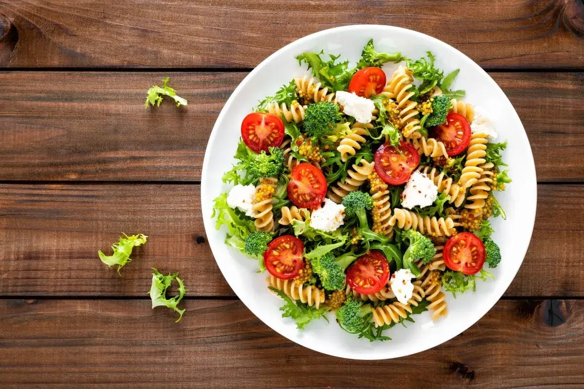 Kolorowa sałatka z makaronem fusilli, pomidorkami koktajlowymi, brokułami i serem feta, polana sosem musztardowym.