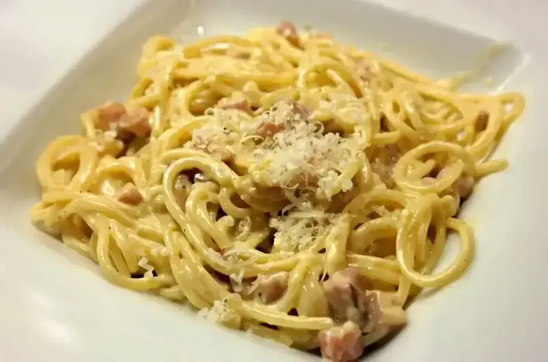 Pyszne spaghetti carbonara z chrupiącym boczkiem, kremowym sosem i parmezanem. Idealne danie dla miłośników włoskiej kuchni.